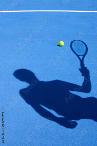 Tennis player silhouette and ball on a blue court.
