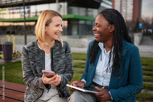 Foto Diverse businesswomen laughing enjoying break with mobile technology
