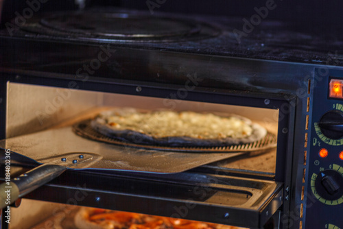 Pizza baking on stone inside hot commercial oven. Melting cheese and rising dough process view.