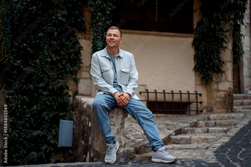 Fototapeta premium Smiling man sitting outdoors in historic European town
