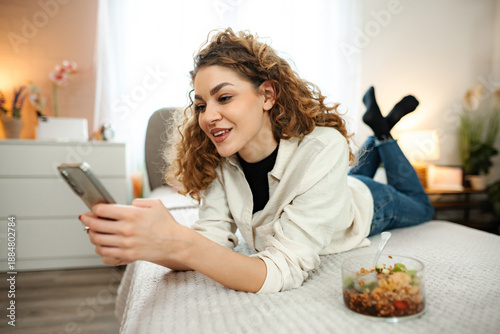 Wallpaper Mural Young woman relaxing in bed using smartphone at home Torontodigital.ca