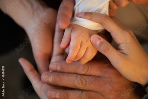 Tableau sur toile Close-up of newborn baby hand gently held by parents, symbol of love, family, care and protection