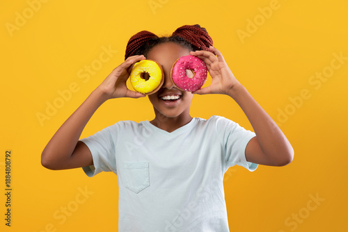 Quadro su tela Funny afro american teen girl in white t-shirt holding colorful delicious donuts