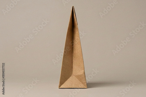 Side profile close up view of a tall triangular cardboard packaging structure on a neutral background