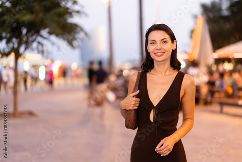 Sticker Positive young woman in summer dress strolling on busy walkway of Barceloneta be