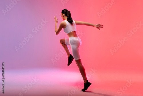 Fotografi Fit woman exercising running over neon pink and peach studio background, full length, copy space