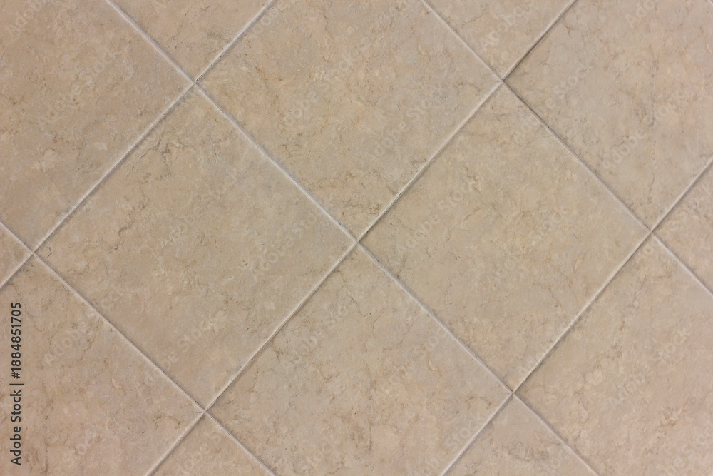 Fototapeta premium Texture of a wall made of beige square ceramic tiles laid out in a pattern close-up