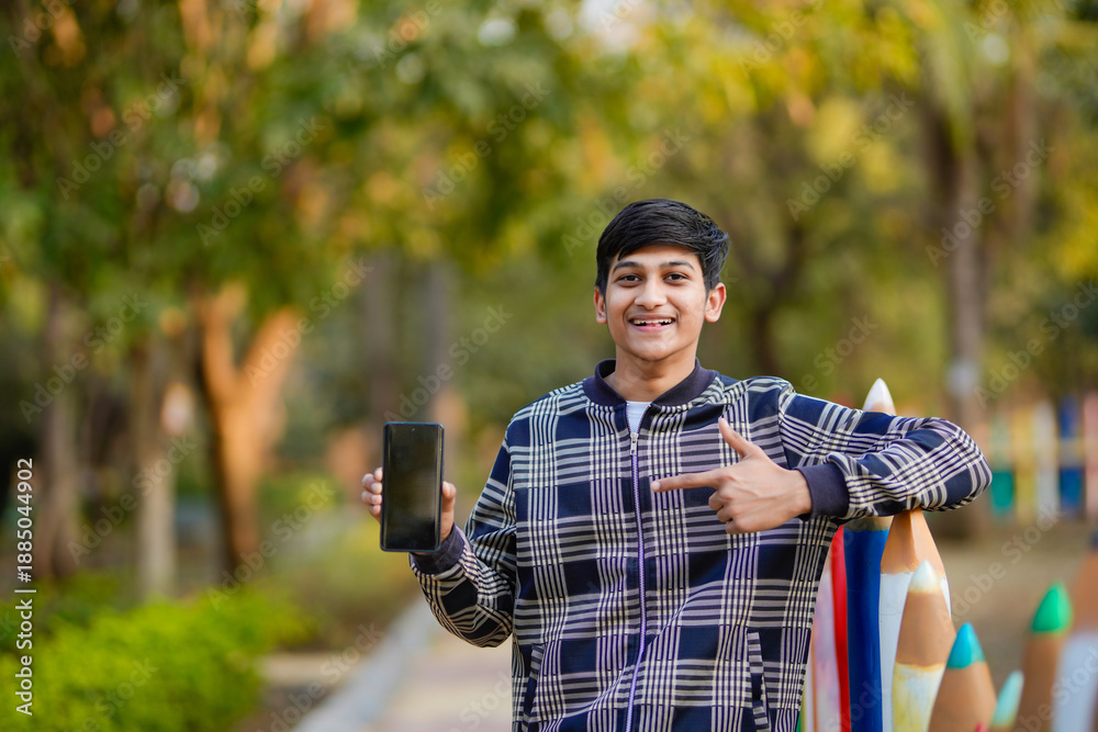 Fototapeta premium young indian teenage boy showing smartphone screen