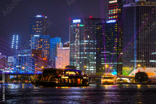 Night view of Bitexco Tower, colorful buildings, Bason bridge and Saigon river in Ho Chi Minh city, tourist boats and cruises on Saigon river