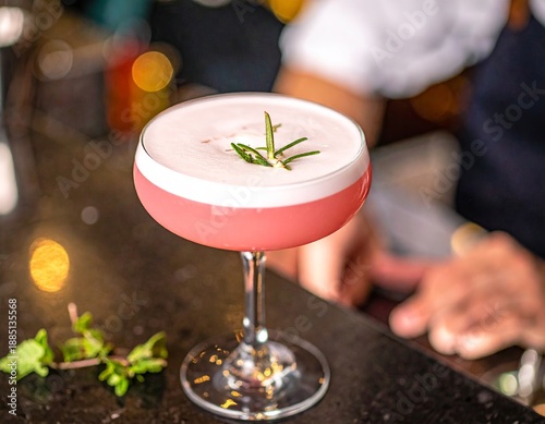  Bebida con espuma y romero en copa elegante en ambiente de bar.
