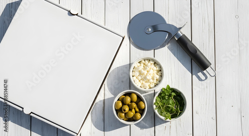 Top view of pizza box with slicer and side dishes on wooden table