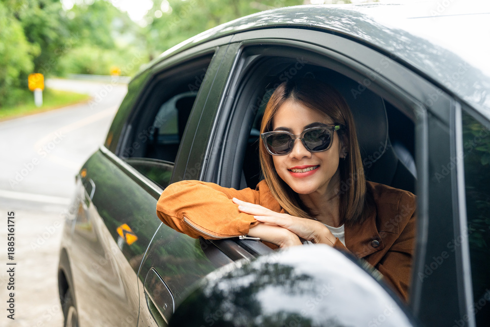 Naklejka premium Young beautiful asian women getting new car. she very happy and excited. Smiling female driving vehicle on the road on a bright day beautiful nature background.