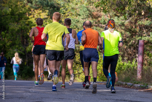 Group male runners running race in city park