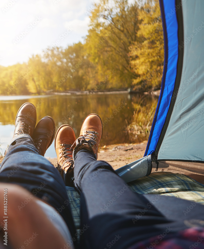 Naklejka premium Couple, shoes and tent by lake for camping, morning and legs or boots with view in nature. Man, woman and relax in woods for camp, adventure and outdoor together for vacation, holiday and travel
