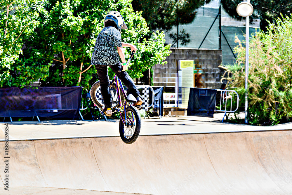 Obraz premium A young man practicing BMX and performing tricks at the skatepark.