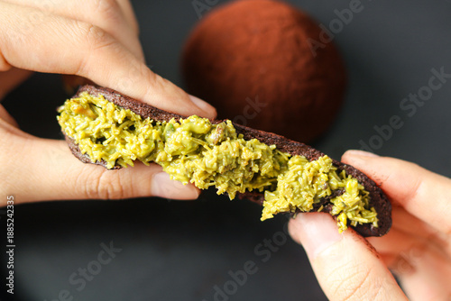 Принти на полотні A hand stretching the Dubai Chewy Cookie with the chewy outer layer opened to reveal the filling of pistachio and kataifi