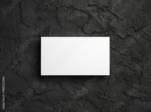 Blank white business card on black textured surface. Template for graphic designers portfolios. Flat lay.