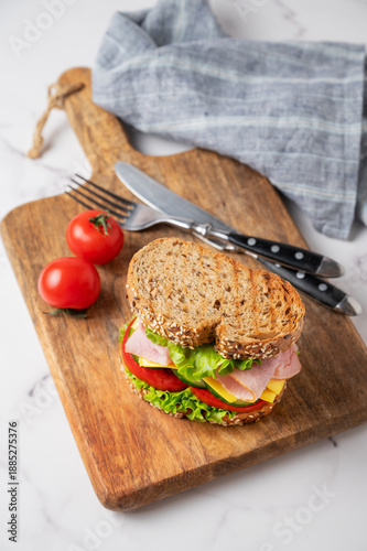 Фотография Sandwich with ham, cheese, lettuce, vegetables and seeded bread on a wooden boar