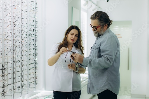 Foto Optician assisting customer choosing new eyeglasses frames