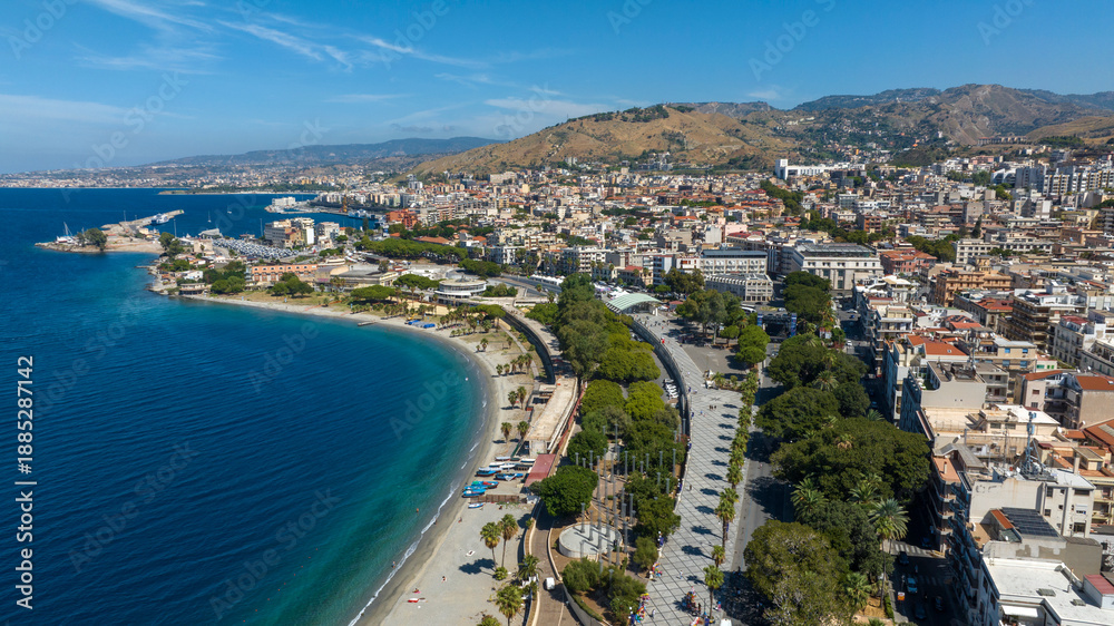 Fototapeta premium Aerial view of Reggio Calabria, a beautiful city overlooking the Mediterranean Sea in southern Italy. It has a long waterfront overlooking the crystal-clear, turquoise sea. It's a sunny summer morning