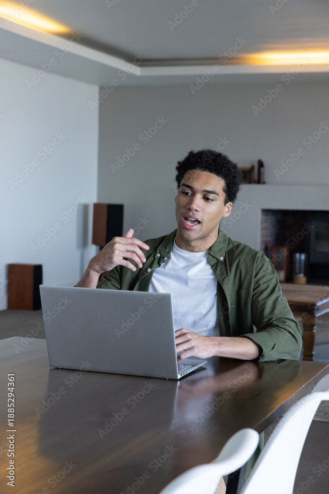 Fototapeta premium African american man sitting at table gesturing during meeting with laptop at home office