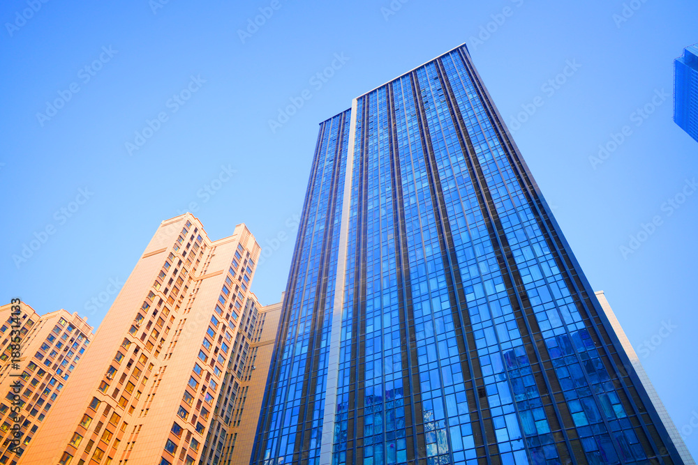 Fototapeta premium Skyscrapers in bright glass exteriors sunlight on sunset. Modern facade office buildings. High-rise bank building in China. Glass facade hotel skyscraper building. Skyscraper modern architecture.