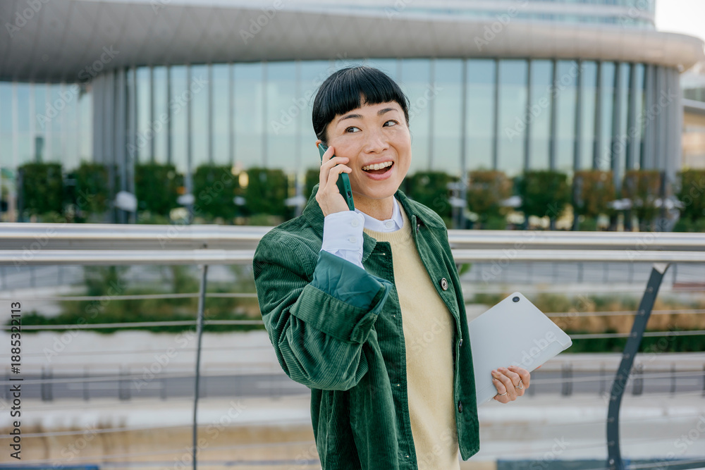 © Westend61 - Confident businesswoman walking outdoors holding tablet and talking on phone