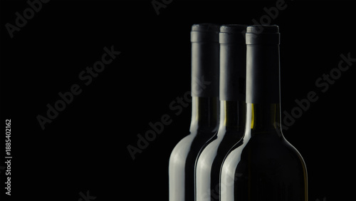 Three wine bottles without labels on a black background