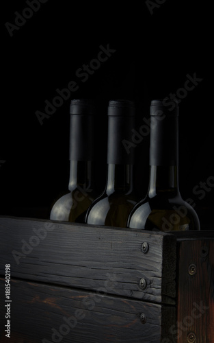 Wine bottles without labels in a wooden box on a dark background