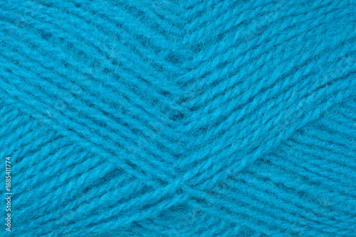 A macro shot showing the detailed texture and fibers of a ball of soft blue wool yarn intertwined in a classic pattern