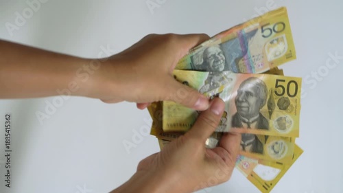 Hands counting Australian dollar banknotes and handing cash to another person, representing payment, financial transaction, income, business exchange, savings, and money management.