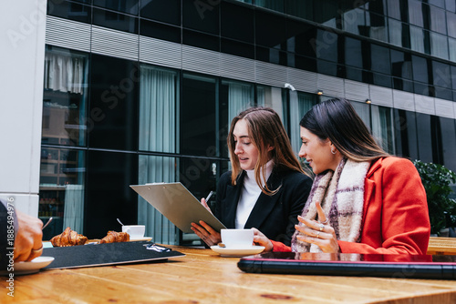 Photos Young Hispanic women teamwork working in the business sector and using laptop ou