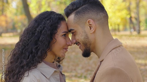 Loving married Hispanic couple touching foreheads noses kissing in autumn park city happy smiling laughing married man woman heads touched outdoors romantic date family tender love affectionate bond