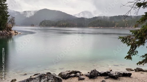 A cinematic horizontal shot of an alpine lake during a rain shower.