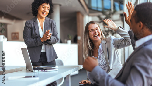 Team Celebration In Office With High Fives Around Laptop During A Happy Meeting