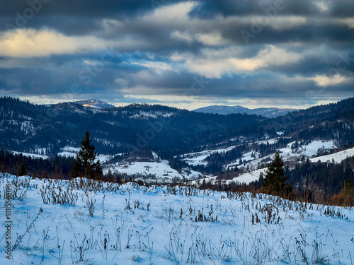 Mystical snowy Carpathian peaks under cloudy skies in the sunny weather