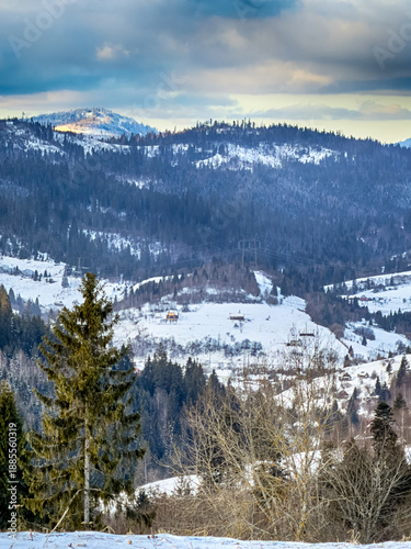 Mystical snowy Carpathian peaks under cloudy skies in the sunny weather