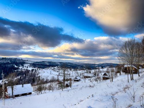 Mystical snowy Carpathian peaks under cloudy skies in the sunny weather