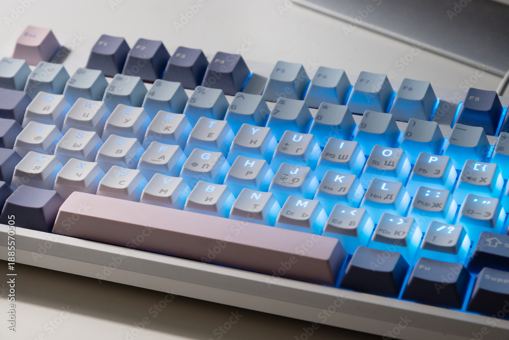 Fototapeta premium Mechanical keyboard with blue LED backlight on desk, modern technology workspace concept.