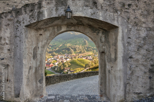 Photos The view through the stone gate under the antique lamp across the green valley towards the nice tiny town and hilly vineyard