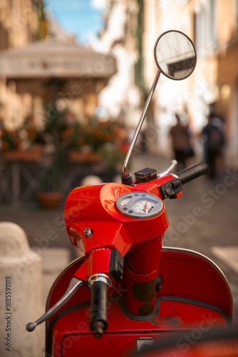 Close-up of a red scooter parked on a bustling European street under a sunny sky. Rome Italy