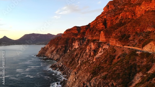 Tableau sur toile calm bay surrounded by glowing red cliffs, distant mountains cast shadows over q