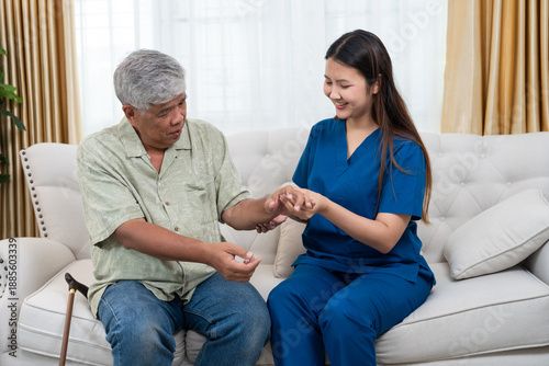 Caring Asian female nurse holding hand of senior man to provide physical therapy at home. Professional caregiver supporting elderly patient with rehabilitation and home healthcare service concept