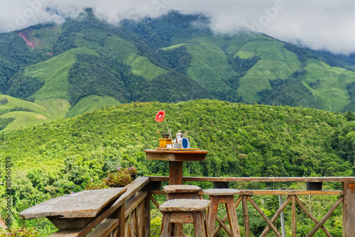 Konstfotografi Coffee set on a wooden table with a view of misty green mountains in the rainy season at Nan, Thailand