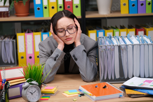 Tableau sur toile A stressed office worker sits at a cluttered desk with piles of documents and colorful sticky notes