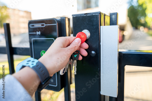 Hand holding house keys unlocks magnetic gate lock to access home property. Residential security scene emphasizes everyday routine, access control, and safety