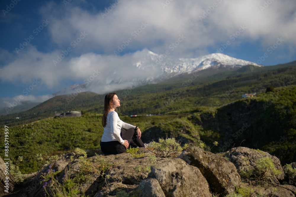 Fototapeta premium Woman Contemplating Majestic Snow-Capped Volcano Amid Lush Green Hills in Tenerife, Canary Islands