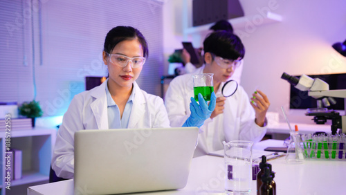 Fotografie Asian female scientist holding a test tube with a solution in gloves in a resear