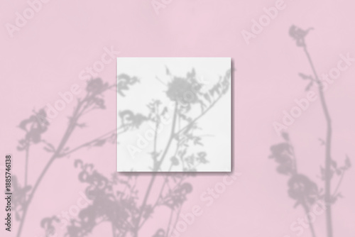 Natural light casts shadows from the wildflowers on square sheet of white paper lying on a pink background. Mockup