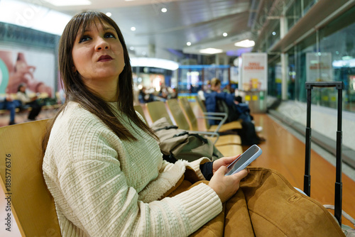 Woman holding phone waiting in airport departure lounge